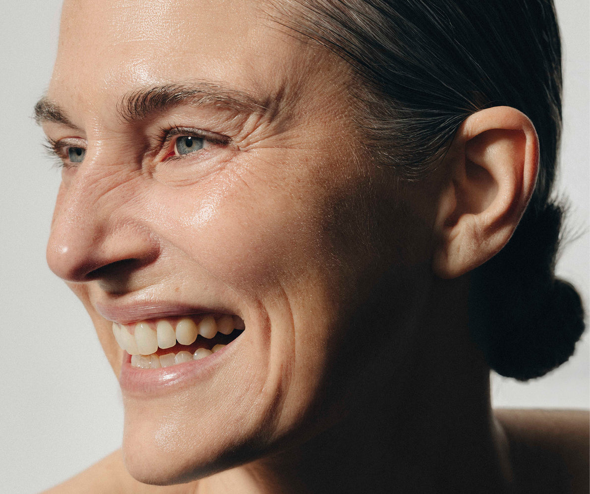 Nahaufnahme einer lachenden Frau im Profil, mit Fältchen an der Nase