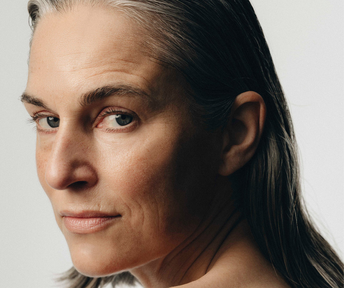 Nahaufnahme eines Frauengesichts von der Seite, über die Schulter blickend, mit leichten Stirnfalten