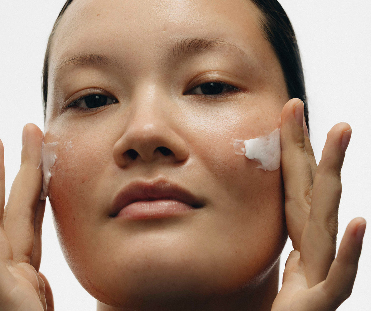 Nahaufnahme einer Frau, die Creme auf ihre Wangen aufträgt