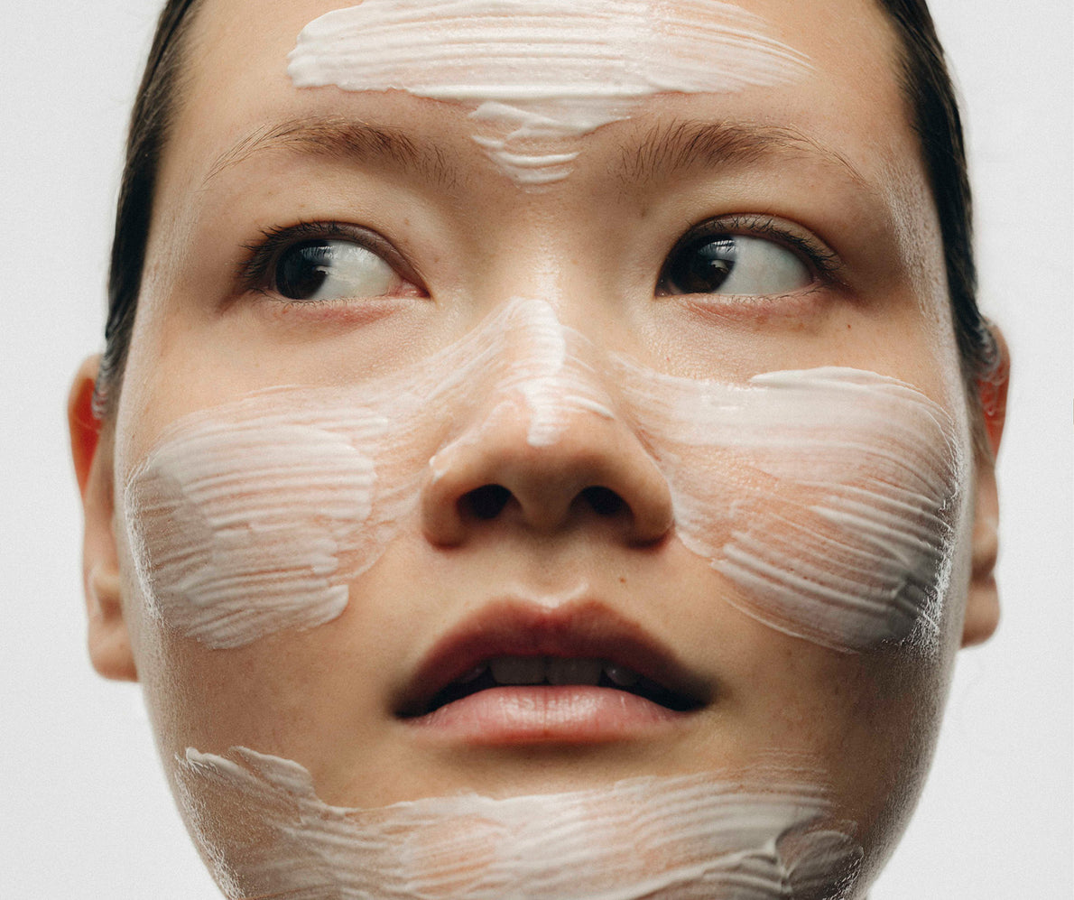 Nahaufnahme einer Frau mit Creme auf Stirn, Wangen und Kinn