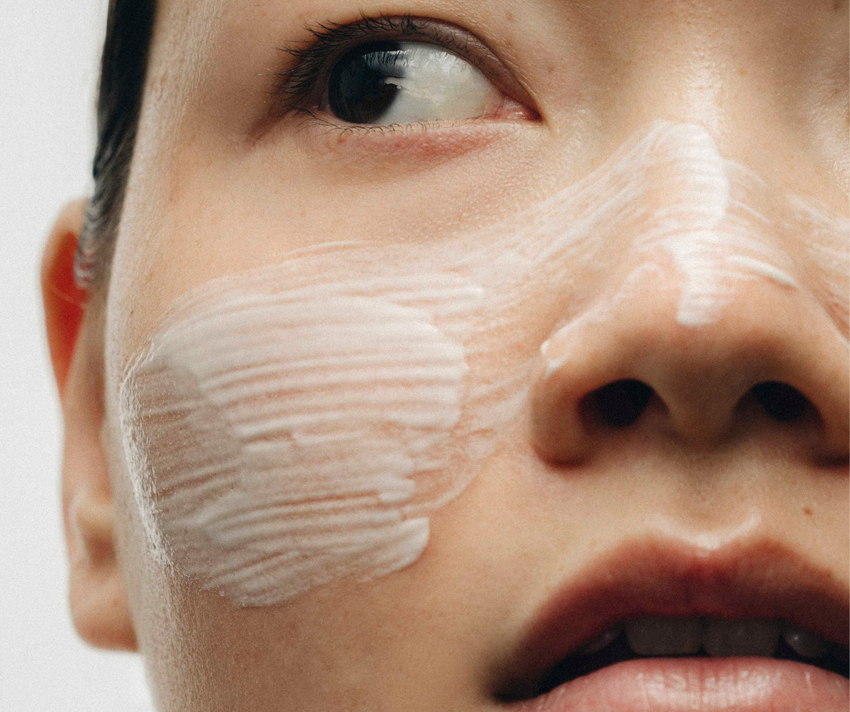 Close-up der Augen- und Nasenpartie einer Frau, Creme auf den Wangen, seitlich schauend